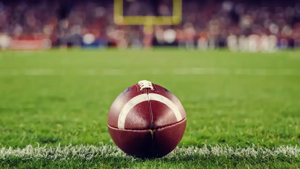 Football close up shot on a football field with grass and goal post in the background
