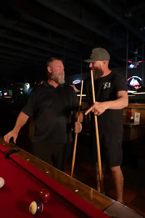 Two men playing pool while talking at the Q Bar