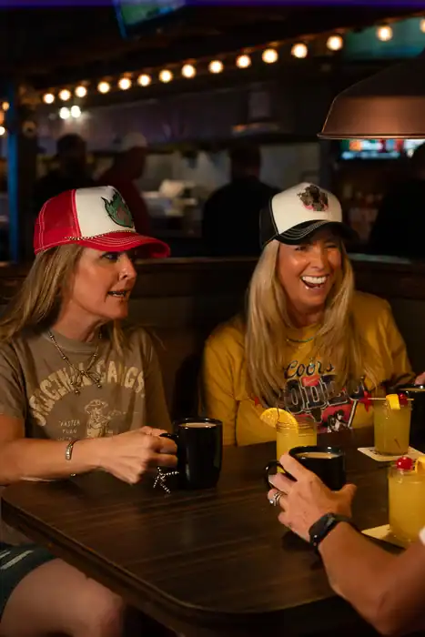 Friends laughing and enjoying mimosas and coffee at Q Bar