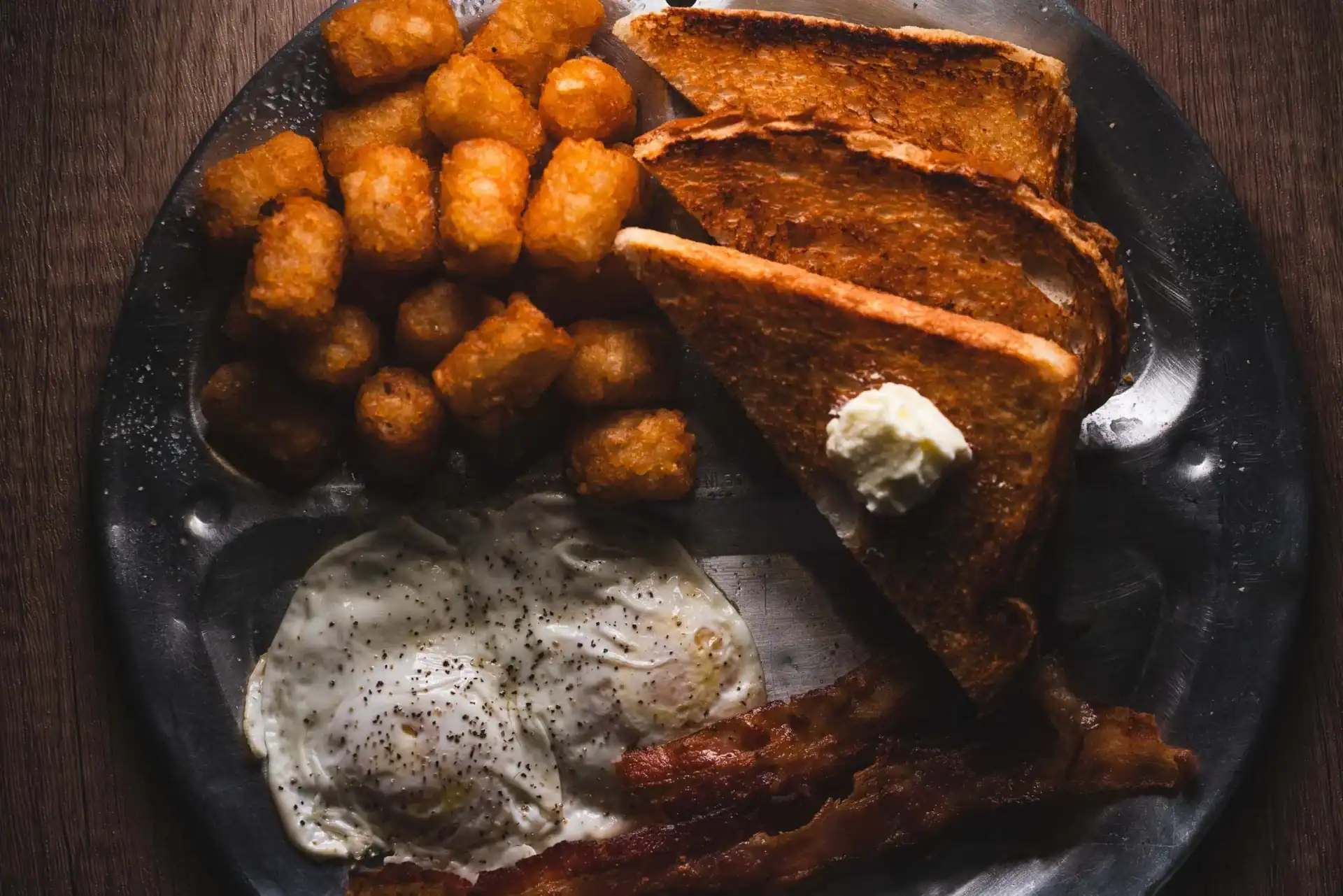 Traditional Sunday breakfast with eggs, bacon, toast, and tater tots at Q Bar & Grill